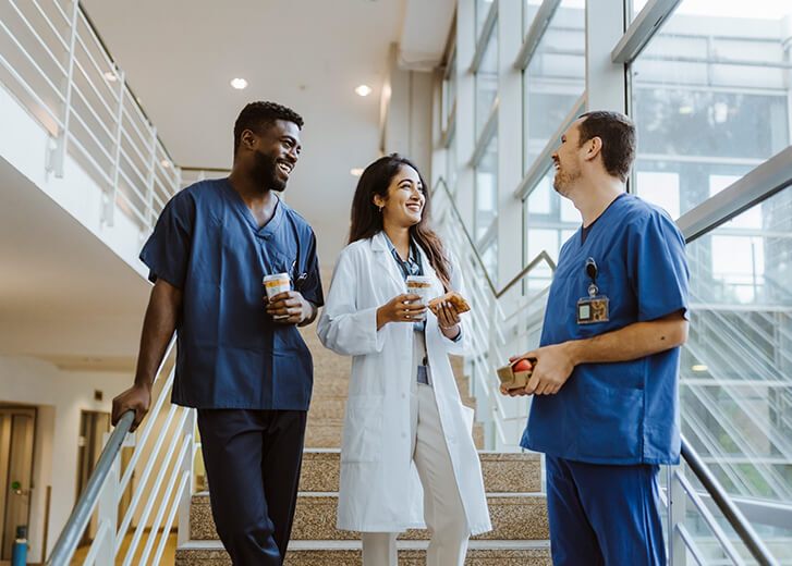  healthcare workers talking while standing on staircase at hospital 